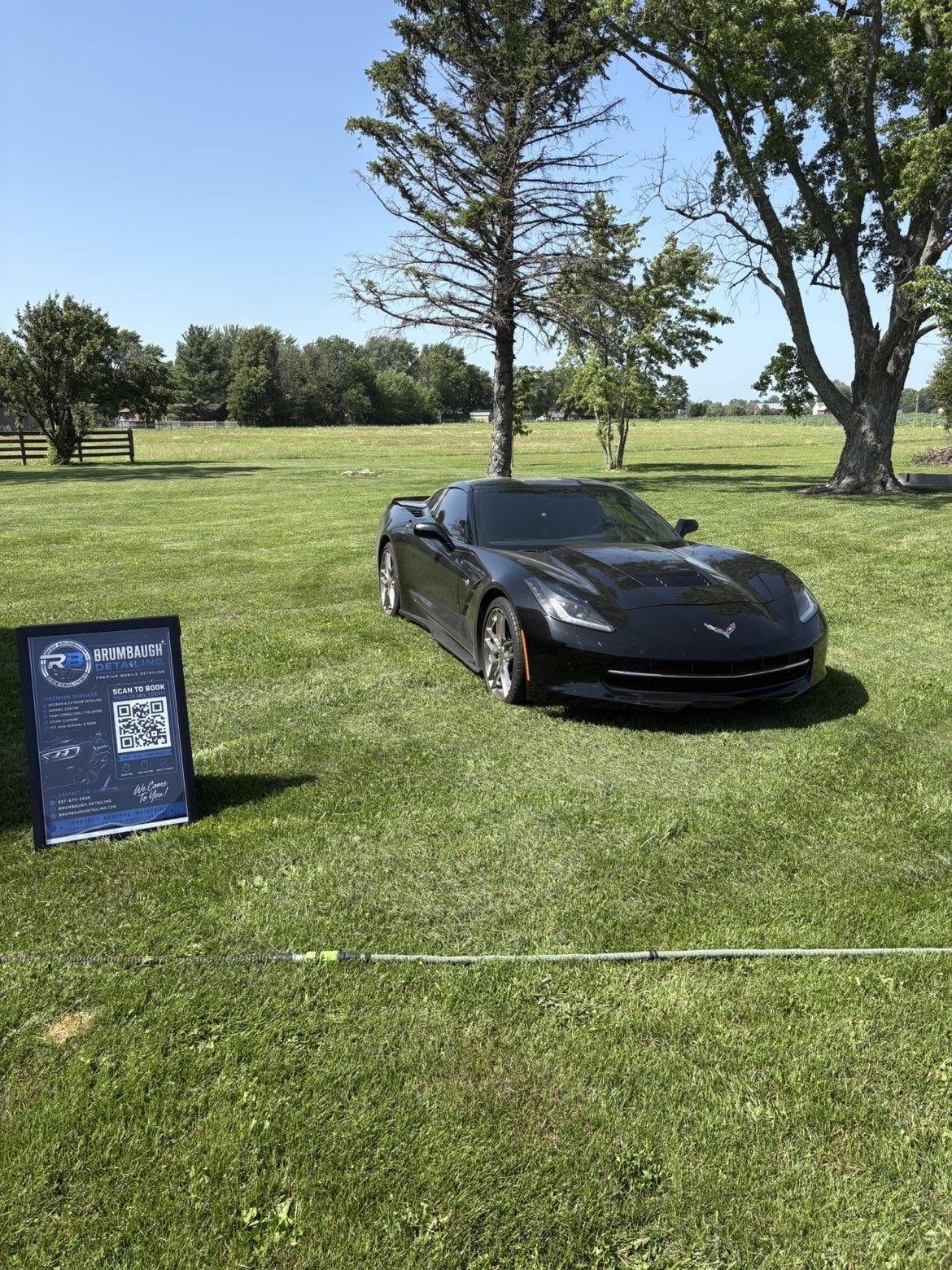 Detailed black Corvette beside the Brumbaugh Detailing sign